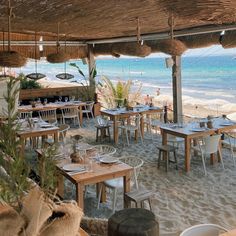 an outdoor dining area with tables and chairs on the beach