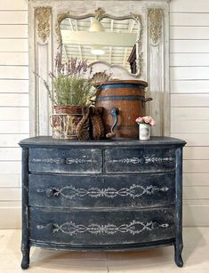 an old dresser with some flowers on top and a potted plant in the middle