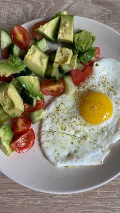 an egg, avocado and tomato salad on a white plate