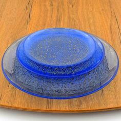 a blue glass plate sitting on top of a wooden table next to a white wall