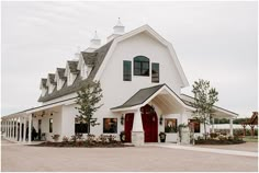 a white barn with red door and windows