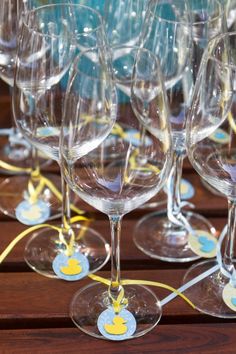 many empty wine glasses are lined up on a wooden table with yellow ribbons around them