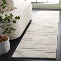 a white rug on the floor next to a potted plant