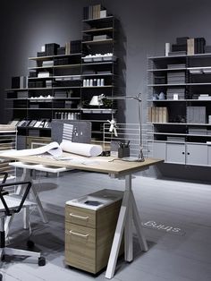 an office with shelves, desks and chairs in the middle of it is shown