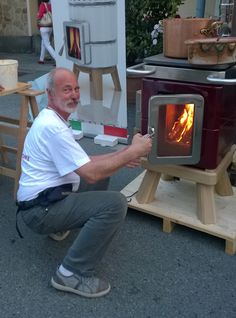 a man kneeling down in front of an open fire oven