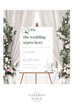 the wedding starts here sign with flowers and greenery in front of a white backdrop