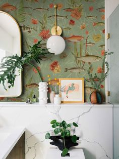 a bathroom with wallpaper and plants on the counter top, along with a mirror