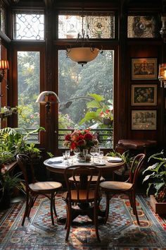 a table and chairs in front of a large window with potted plants on it