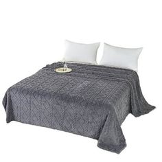 a bed with two white pillows on top of it and a gray bedspread