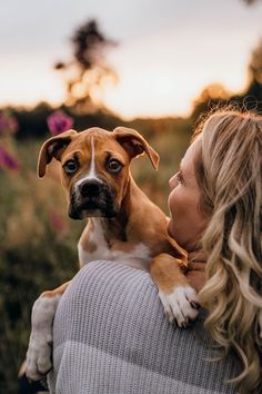 a woman holding a brown and white dog in her arms