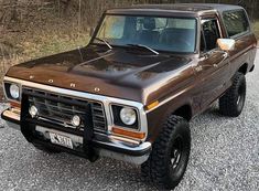 a brown truck parked on top of a gravel road