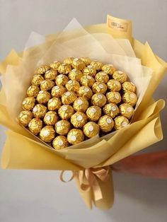 a person holding a bouquet of chocolates in it's hand and wrapped in yellow paper