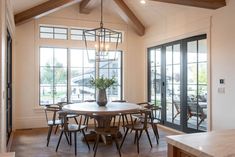 a dining room table with chairs and a vase on the table in front of glass doors