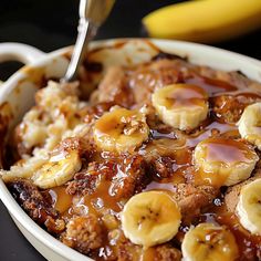 a white bowl filled with bananas and caramel on top of a black table next to a banana peel