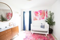 a white baby crib sitting in a room next to a dresser and window with blue curtains