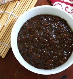 a white bowl filled with black beans on top of a wooden table next to chopsticks