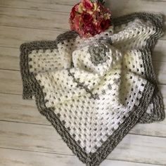 two crocheted place mats and a flower on a wooden table with white boards