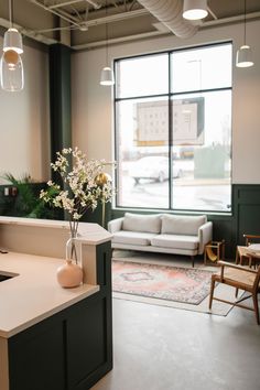 a vase with flowers sitting on top of a counter in front of a large window