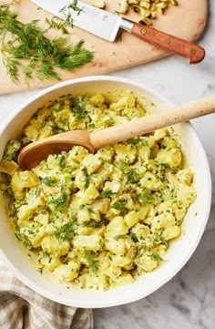 a white bowl filled with scrambled eggs on top of a counter next to a cutting board