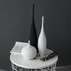 three white and black vases sitting on top of a table