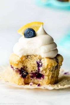 a blueberry muffin with white frosting and a lemon slice on top is shown