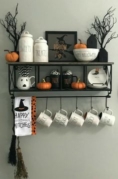 a shelf with coffee mugs and halloween decorations on it, hanging from the wall