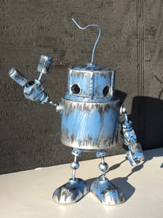 a blue and white robot statue sitting on top of a table next to a wall