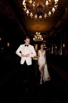 a man in a tuxedo standing next to a woman in a white dress