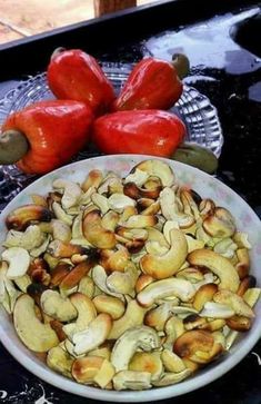 a bowl filled with nuts next to two red peppers