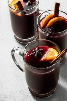 two mugs filled with mulled wine and cinnamon sticks