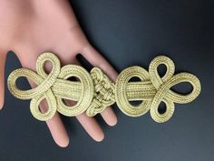 a close up of a person's hand wearing a gold bracelet with knots on it