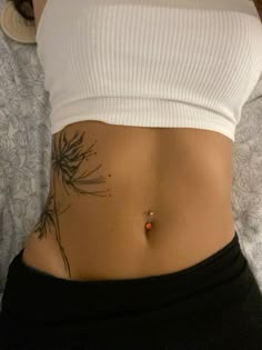 a woman's stomach with a tattoo on the side and an orange bead at the bottom