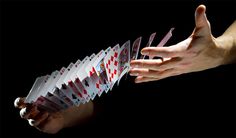 several playing cards being held by two hands