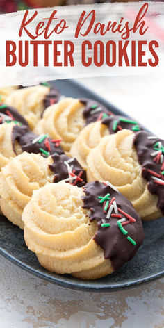 Chocolate dipped keto butter cookies with holiday sprinkles lined up on a black tray. Keto Danish, Keto Butter Cookies, Danish Butter Cookies, Low Carb Holiday