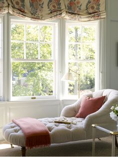 a living room filled with furniture and a window covered in floral drapes next to a coffee table