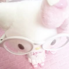 a stuffed animal wearing glasses on top of a bed