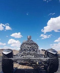 a large four - wheeled vehicle is parked on the road with clouds in the background