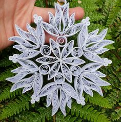 a paper snowflake ornament being held by someone's hand