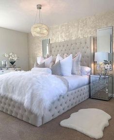 a large white bed sitting in a bedroom next to a mirror