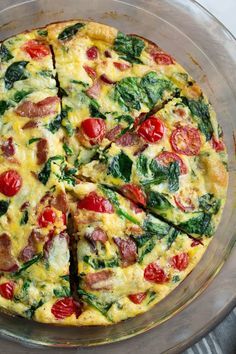 an omelet with spinach, tomatoes and sausage is cut into four pieces