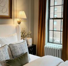 a white bed sitting next to a window in a bedroom