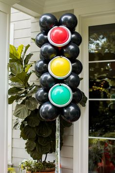 a traffic light made out of balloons sitting on the side of a building next to a potted plant