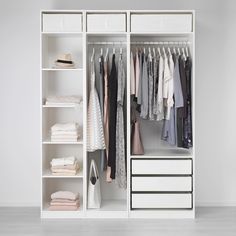 an open white closet with clothes hanging on the shelves and drawers in front of it