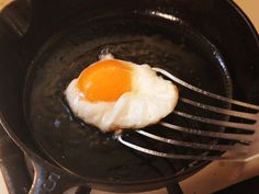 an egg frying in a skillet with a fork sticking out of it's side