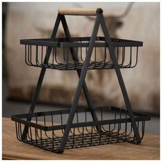 a three tiered metal basket on top of a wooden table