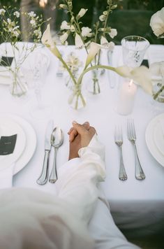 a person sitting at a table with silverware and flowers