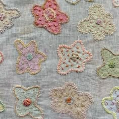 many different colored embroidered flowers on a gray cloth