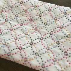 a close up of a white quilt on a table cloth with multicolored dots