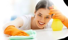 a woman cleaning the table with a sponge and detergent on her head while smiling at the camera