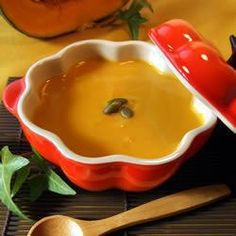 a red bowl filled with soup next to a wooden spoon on top of a table